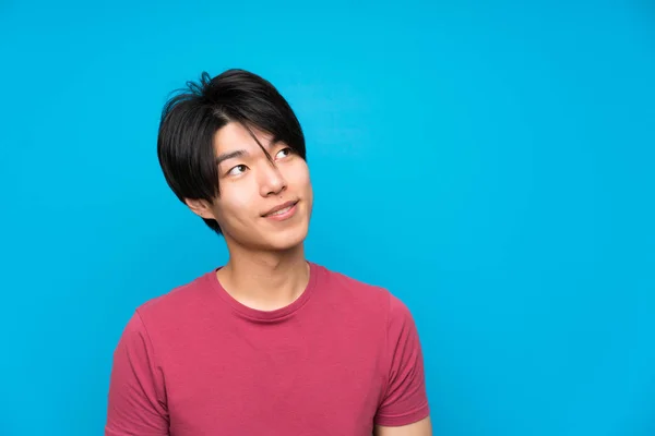 Hombre Asiático Con Camisa Roja Sobre Pared Azul Aislada Riendo —  Fotos de Stock