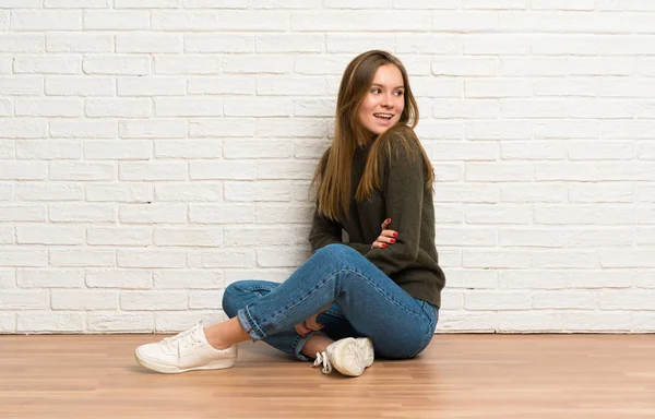 Νεαρή Γυναίκα Που Κάθεται Στο Πάτωμα Σταυρωμένα Χέρια Και Ευτυχισμένη — Φωτογραφία Αρχείου