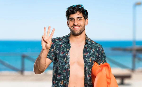 Άντρας Μπαούλα Είναι Χαρούμενος Και Μετράει Τρεις Δάχτυλα Στην Παραλία — Φωτογραφία Αρχείου