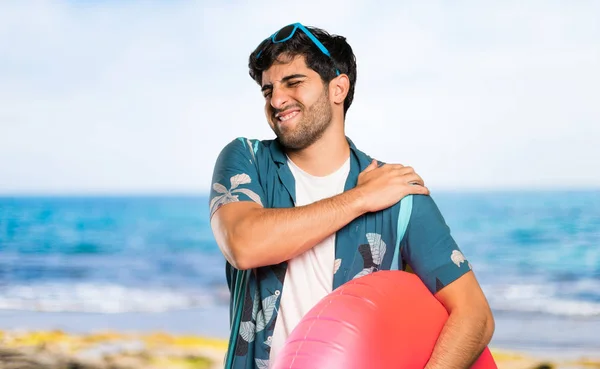 Man in trunks suffering from pain in shoulder for having made an effort at the beach