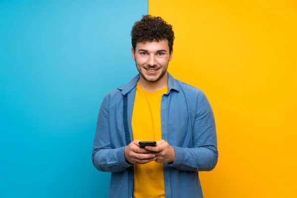 Mann Mit Lockigem Haar Über Bunte Wand Sendet Eine Nachricht — Stockfoto