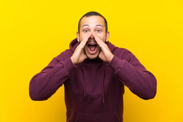 Hombre Colombiano Con Sudadera Sobre Pared Amarilla Gritando Anunciando Algo — Foto de Stock