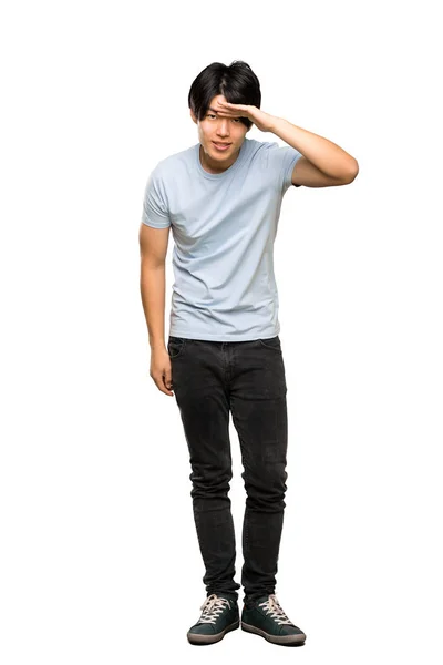 青いシャツを着たアジア人男性が 孤立した白い背景の上に何かを見るために手で遠くを見ているのを完全な長さのショット — ストック写真