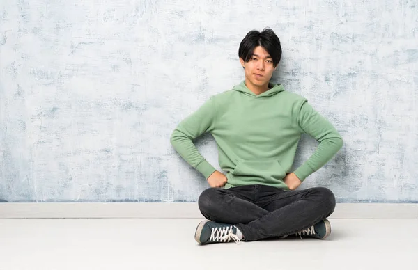 Asian man sitting on the floor angry