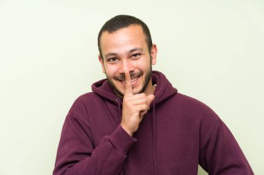 Yeşil duvar üzerinde sweatshirt ile Kolombiyalı adam sessizlik jest yapıyor