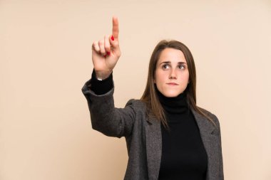 İzole edilmiş duvarın üstünde genç bir kadın şeffaf ekrana dokunuyor.