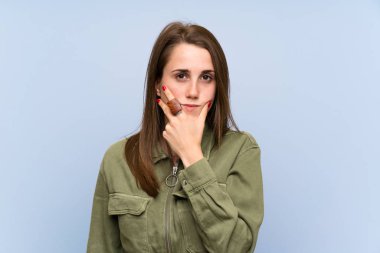 Izole mavi duvar ayakta ve bir fikir düşünme üzerinde genç kadın