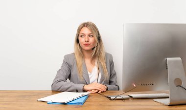 Kulaklıkla çalışan genç bir kadın ayakta duruyor ve yana bakıyor.