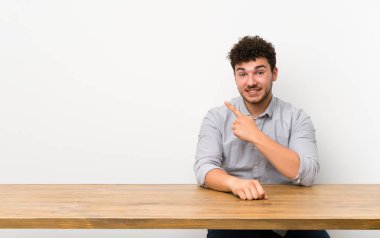 Bir ürün sunmak için yan işaret eden bir tablo ile genç adam