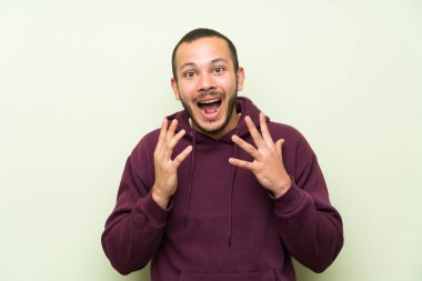Sürpriz yüz ifadesi ile yeşil duvara Sweatshirt ile Kolombiyalı adam