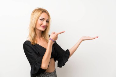 Bir reklam eklemek için avuç üzerinde copyspace hayali tutan izole beyaz duvar üzerinde genç sarışın kadın