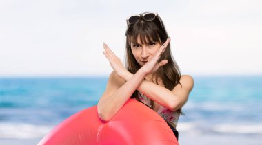 Bikinili genç bir kadın sahilde jest yapmıyor.