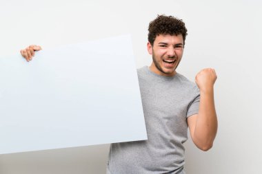 Bir kavram eklemek için boş bir beyaz pankart tutan izole duvar üzerinde kıvırcık saçlı adam