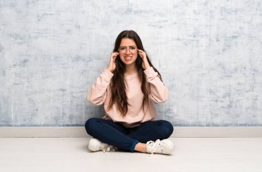 Genç öğrenci kız bir masada sinirli ve kulakları kapsayan eğitim