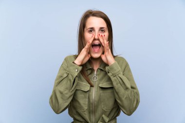 Ağzı tamamen açık bağıran izole mavi duvar üzerinde genç kadın