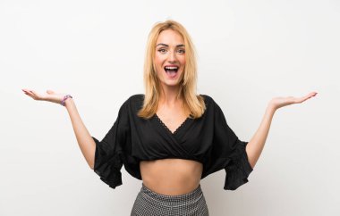 Şok yüz ifadesi ile izole beyaz duvar üzerinde genç sarışın kadın