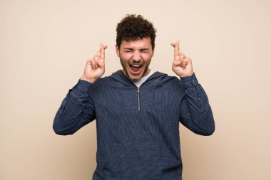 Parmakları geçerken izole duvar üzerinde kıvırcık saçlı adam