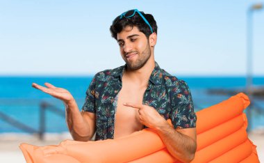 Plaja bir reklam eklemek için avuç içinde copyspace hayali tutan şort adam