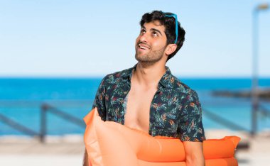 Şortlu adam mutlu ve plajda gülümsüyor