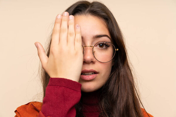 Teenager girl with coat covering a eye by hand