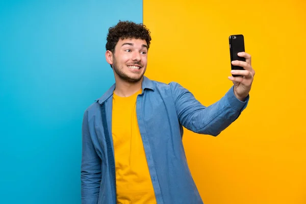 Renkli Duvar Üzerinde Kıvırcık Saçlı Adam Selfie Yapıyor — Stok fotoğraf