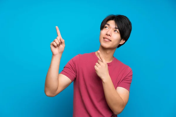 Asiatique Homme Avec Chemise Rouge Sur Isolé Mur Bleu Pointant — Photo