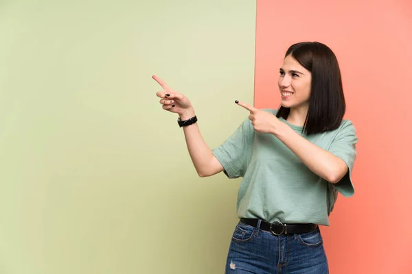 Jonge Vrouw Geïsoleerde Kleurrijke Muur Wijzende Vinger Aan Zijkant — Stockfoto