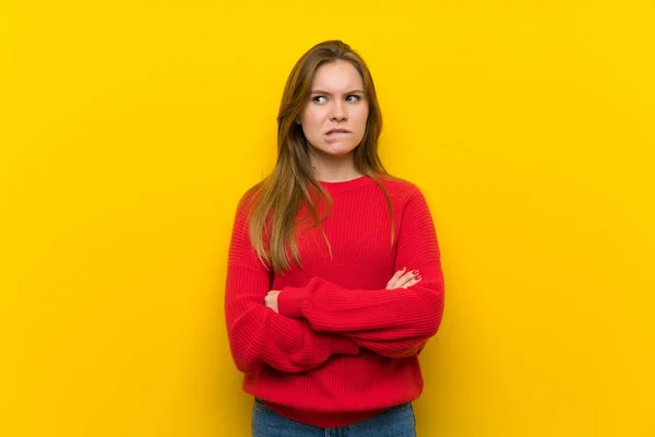 Young woman over yellow wall with confuse face expression