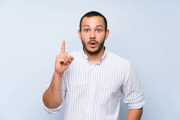 Hombre Colombiano Sobre Aislado Muro Azul Pensando Una Idea Apuntando —  Fotos de Stock