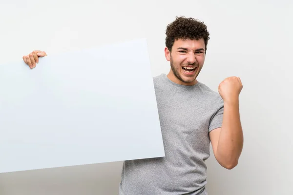 Człowiek Kręconymi Włosami Nad Izolowaną Ścianą Posiadając Pusty Biały Afisz — Zdjęcie stockowe