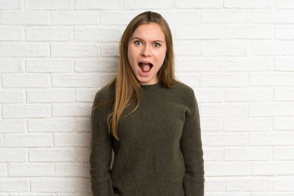 Jovem Mulher Sobre Parede Tijolo Branco Com Expressão Facial Surpresa — Fotografia de Stock