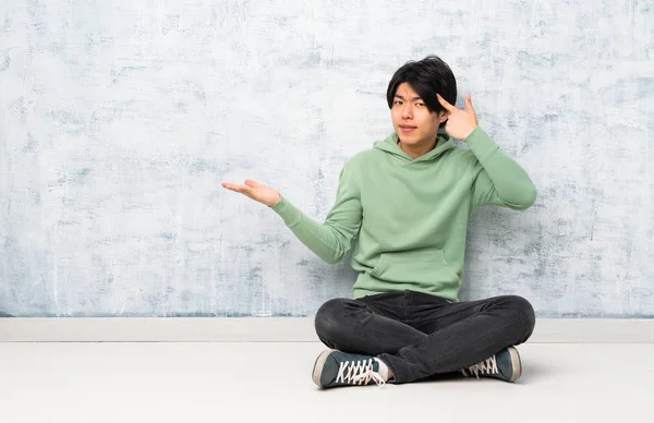 Asiatischer Mann Sitzt Auf Dem Boden Und Macht Die Geste — Stockfoto