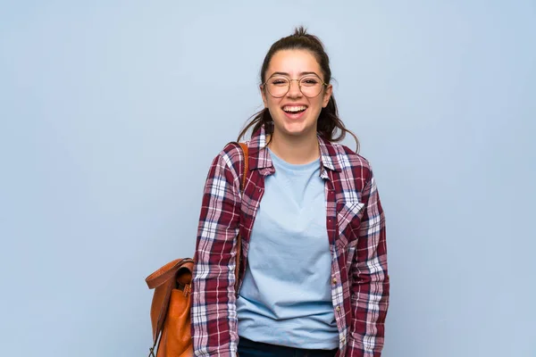 Teenager student girl over isolated blue wall smiling