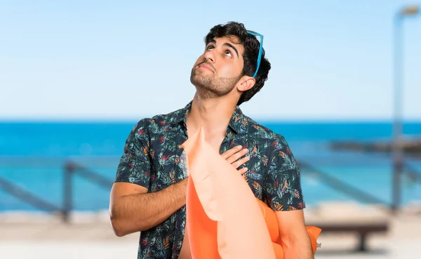 Man in trunks looking up while smiling at the beach