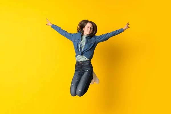 若いです女性ジャンプ上の黄色の背景 — ストック写真