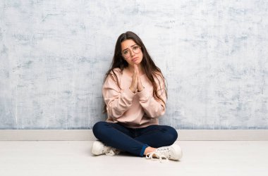 Bir masada okuyan genç öğrenci kız avuç içi bir arada tutar. Kişi bir şey ister