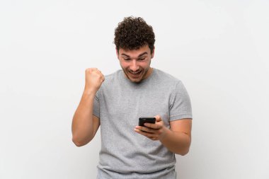 Cep telefonu kullanarak izole duvar üzerinde kıvırcık saçlı adam