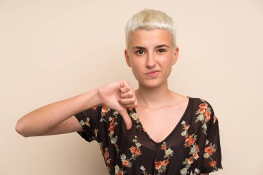 İzole edilmiş duvarın üstünde genç bir kadın baş parmağı aşağı işareti gösteriyor.