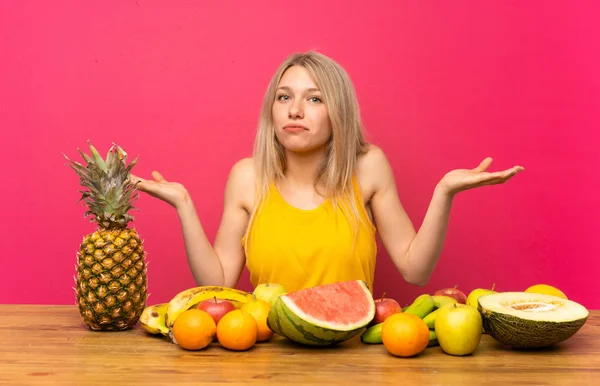 Young Blonde Woman Lots Fruits Having Doubts Confuse Face Expression — Stock Photo, Image