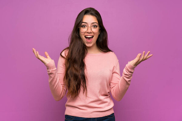 Teenager girl over purple wall smiling a lot