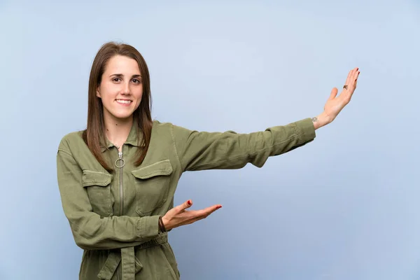 Jonge Vrouw Geïsoleerde Blauwe Muur Strek Handen Naar Zijkant Voor — Stockfoto