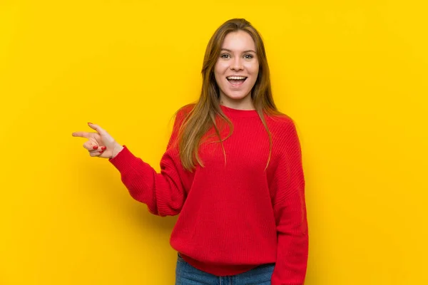 黄色の壁側に人差し指の上の若い女性 — ストック写真