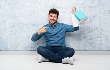 Yerde oturan genç adam elinde bir sürü alışveriş çantasıyla