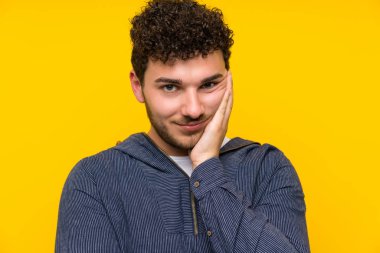 İzole edilmiş sarı duvarlı genç adam mutsuz ve sinirli.