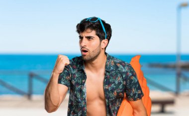 Sandıklı adam plajda kazanan pozisyonda bir zafer kutluyor