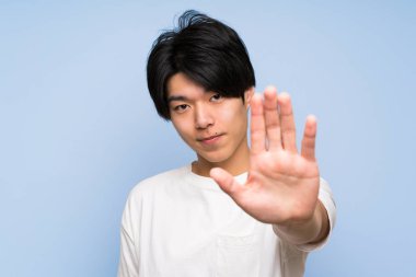İzole mavi arka plan asyalı adam eliyle stop jest yapma
