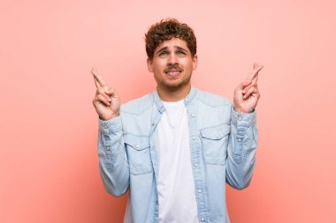 Parmakları geçiş ve en iyi dilek ile pembe duvar üzerinde Blonde adam