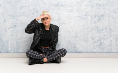 Genç bir kadın yerde oturuyor. Bir şeye bakmak için uzaklara bakıyor.