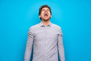Mavi duvar ile ağız açık ön bağıran sarışın adam