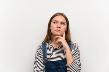 Kot pantolonlu genç bir kadın beyaz duvarın üstünde bir fikir düşünüyor.